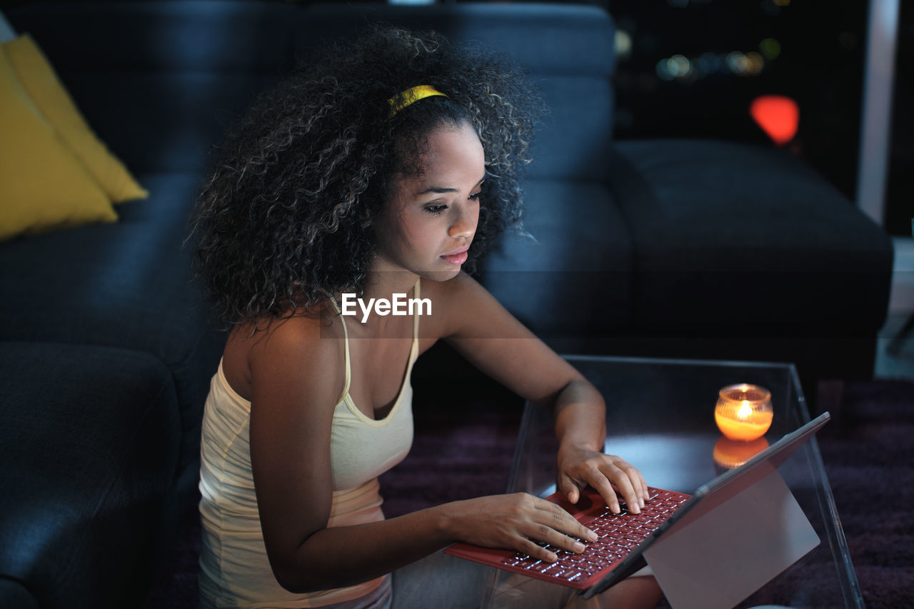 High angle view of young woman using digital tablet on table at home