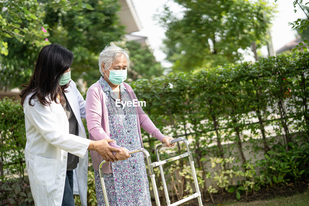 WOMAN STANDING BY PLANTS