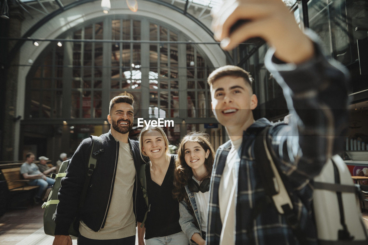 Cheerful family taking selfie together while standing at station