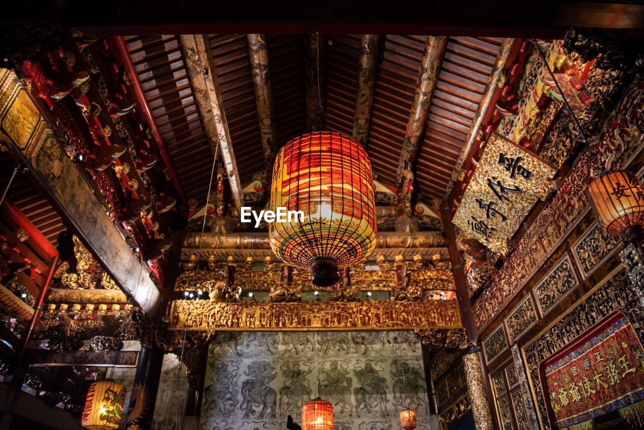 Low angle view of illuminated lantern hanging from ceiling of temple 