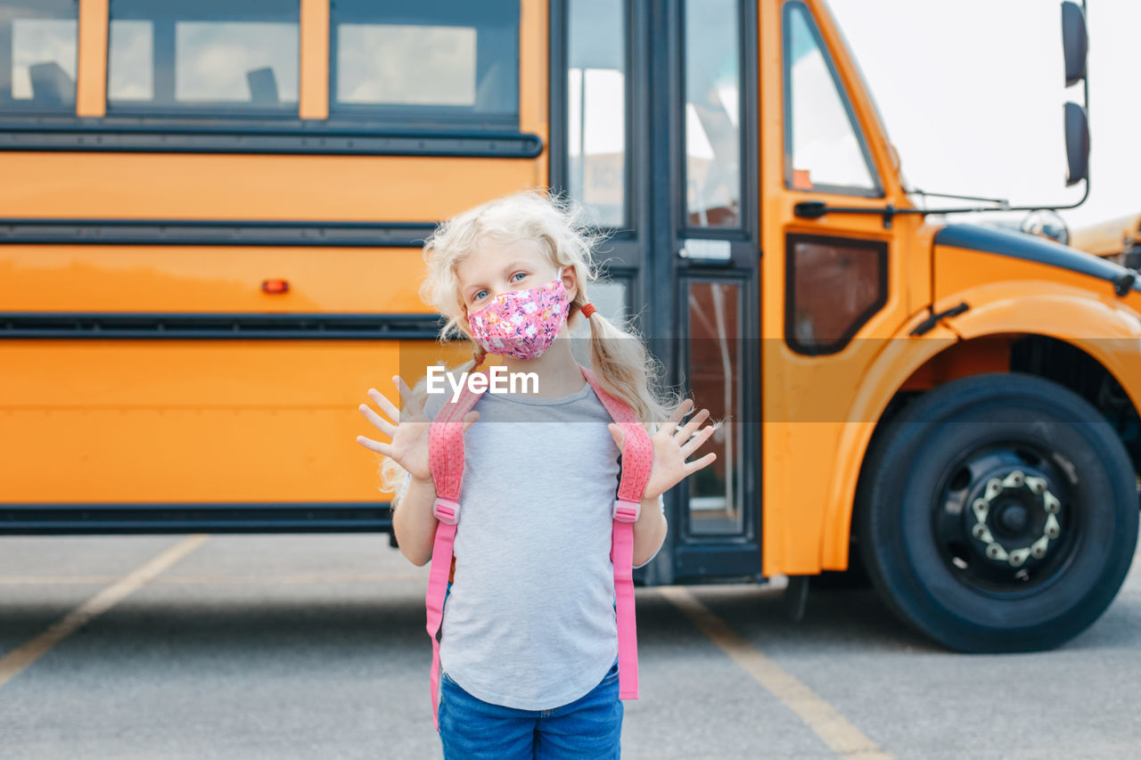 Portrait of girl standing against bus