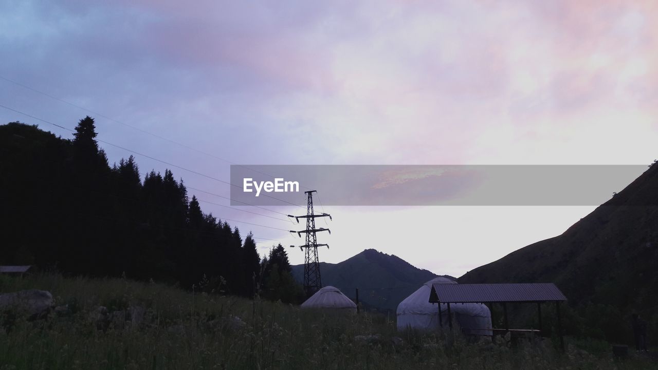 LOW ANGLE VIEW OF ELECTRICITY PYLON AND MOUNTAINS AGAINST SKY