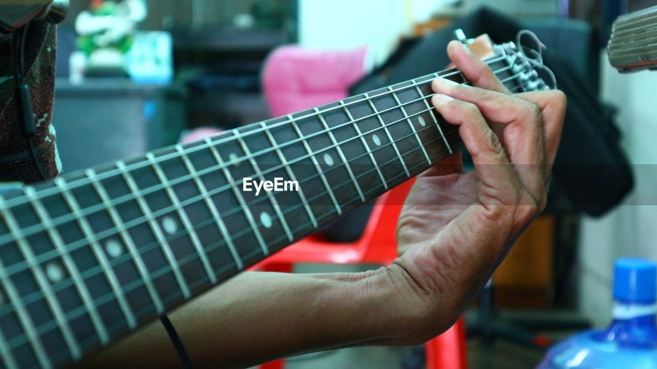 Cropped hand playing guitar at home