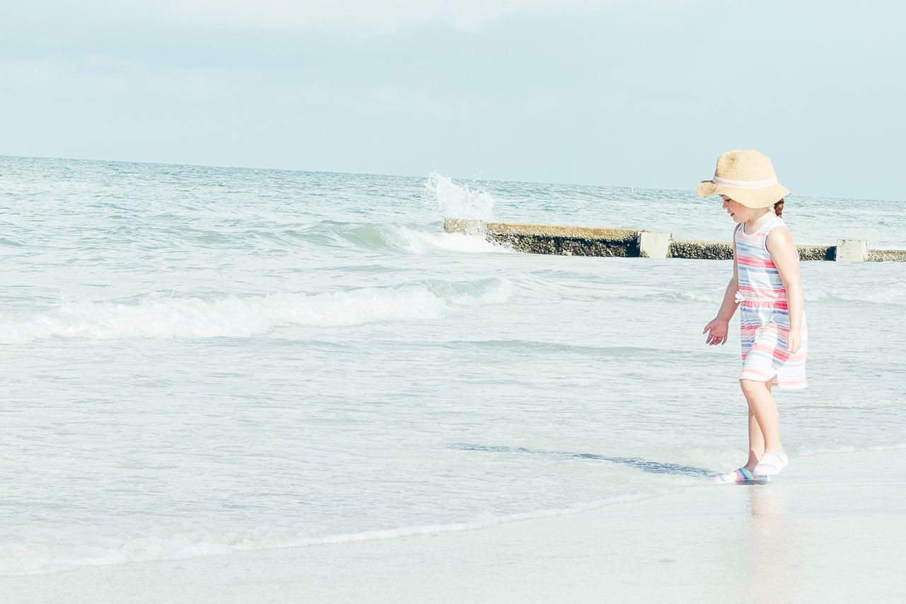 MAN STANDING ON BEACH AGAINST SEA