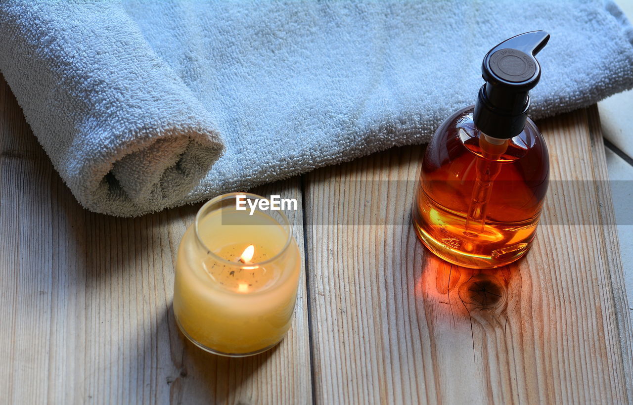 High angle view of tea light candle and oil bottle on table at beauty spa