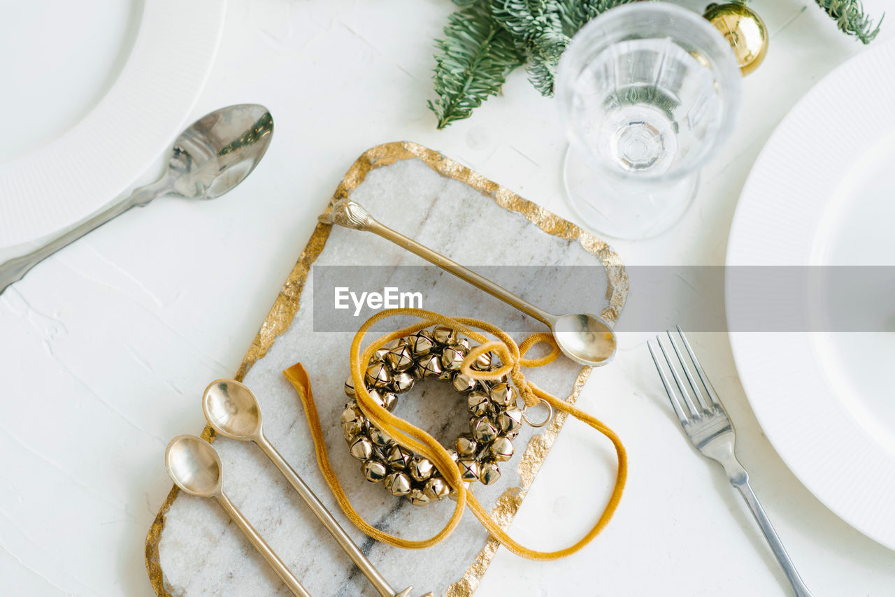 Christmas wreath of golden bells in the decoration of the festive dinner. cutlery on a marble board