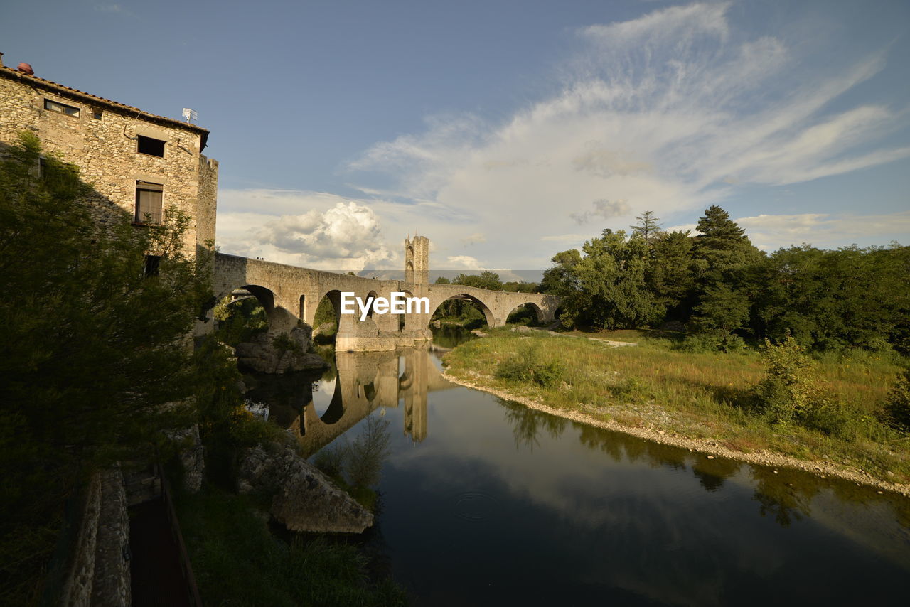 Arch bridge over lake against buildings