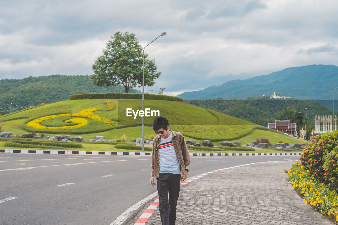 Man walking on sidewalk against sky