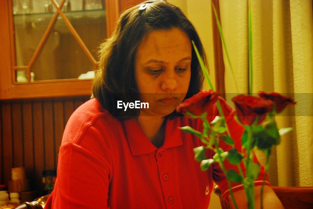 Woman in red holding red rose