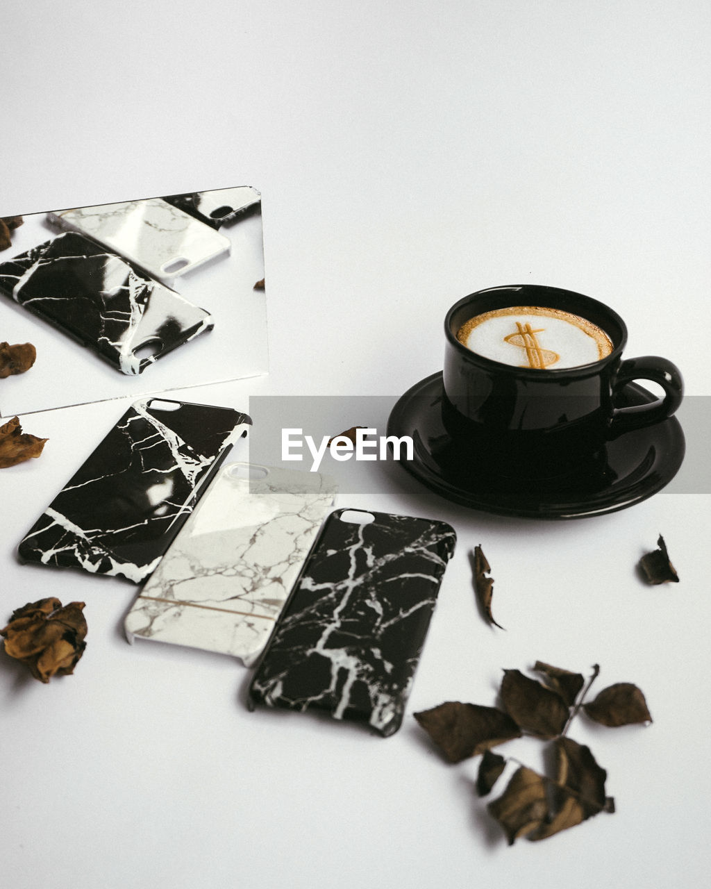 Close-up of coffee by phone covers on white table