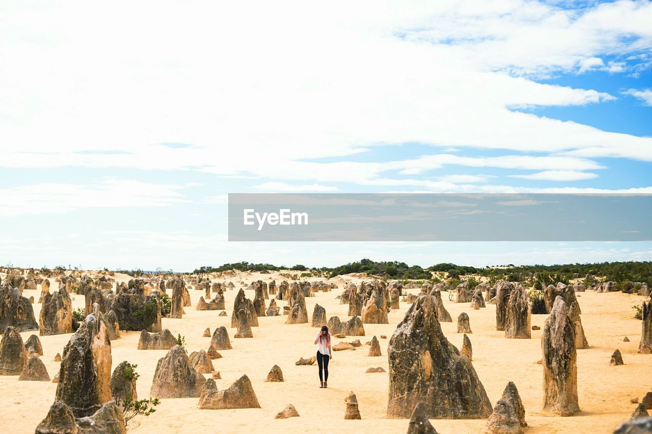 Woman standing by limestones at nambung national park against sky