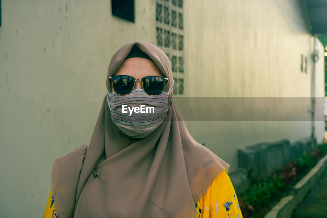 Portrait of woman wearing sunglasses standing against city