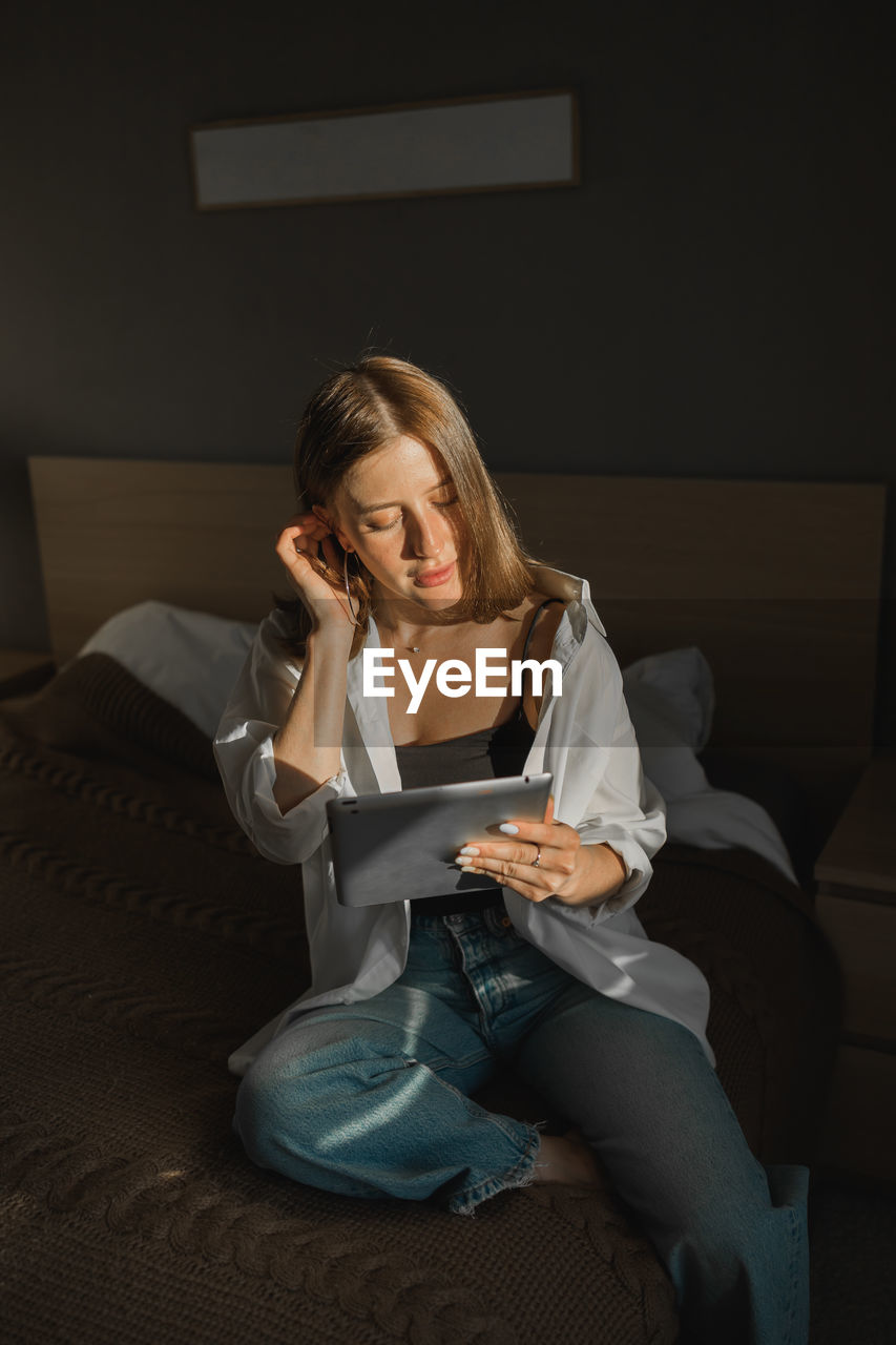 portrait of woman using mobile phone while sitting on sofa at home