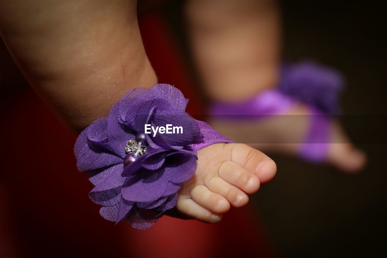Close-up of baby legs with artificial flowers decoration