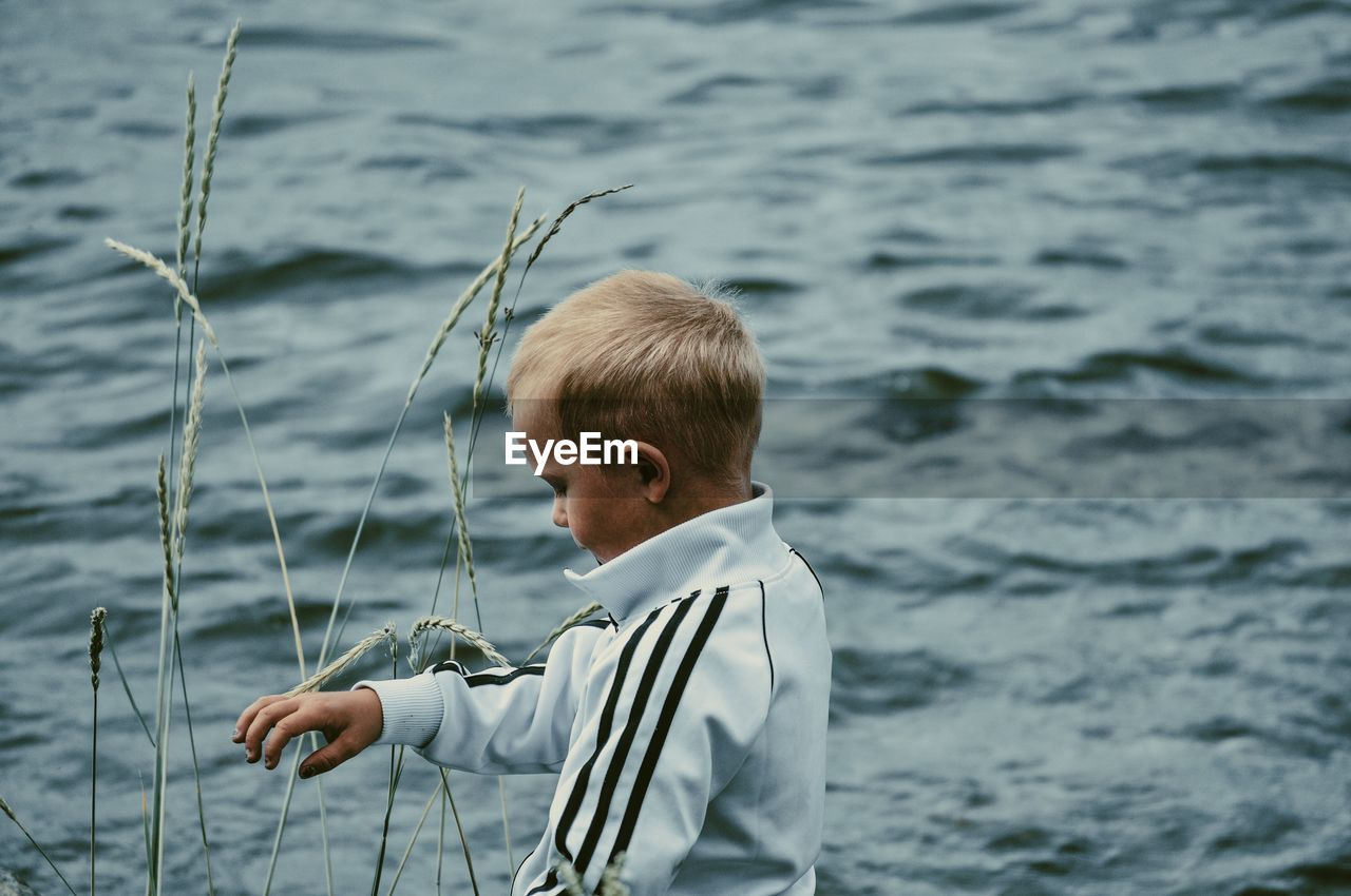 BOY STANDING BY SEA