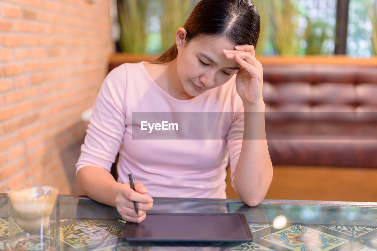 YOUNG WOMAN USING PHONE ON TABLE