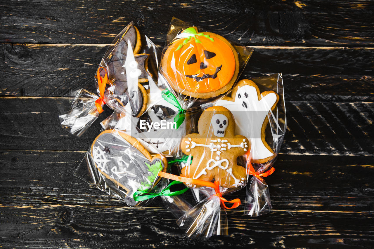 High angle view of various cookies wrapped in plastic on wooden table during halloween