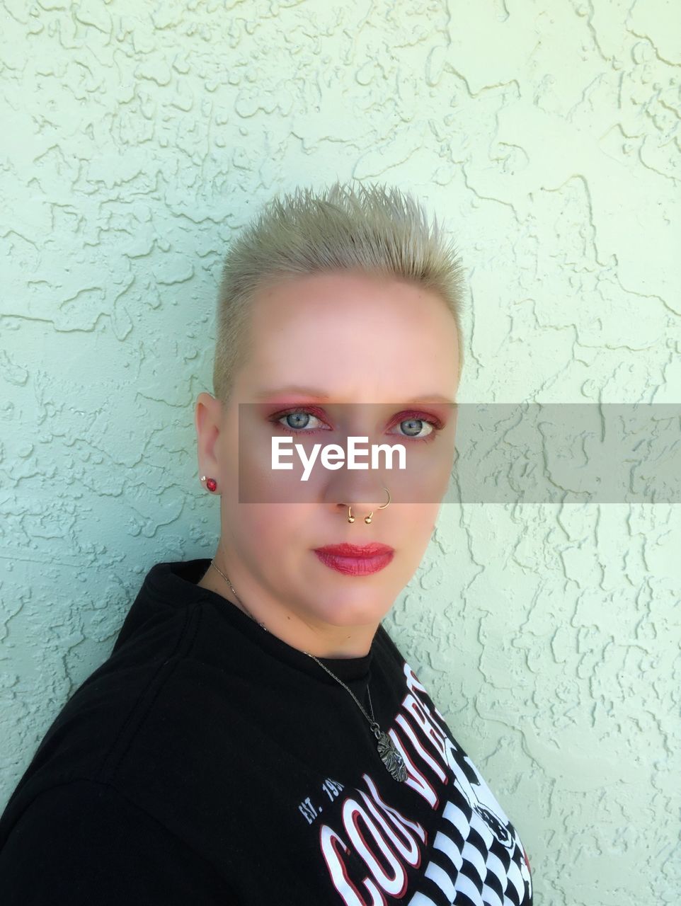 Portrait of woman with short hair against wall