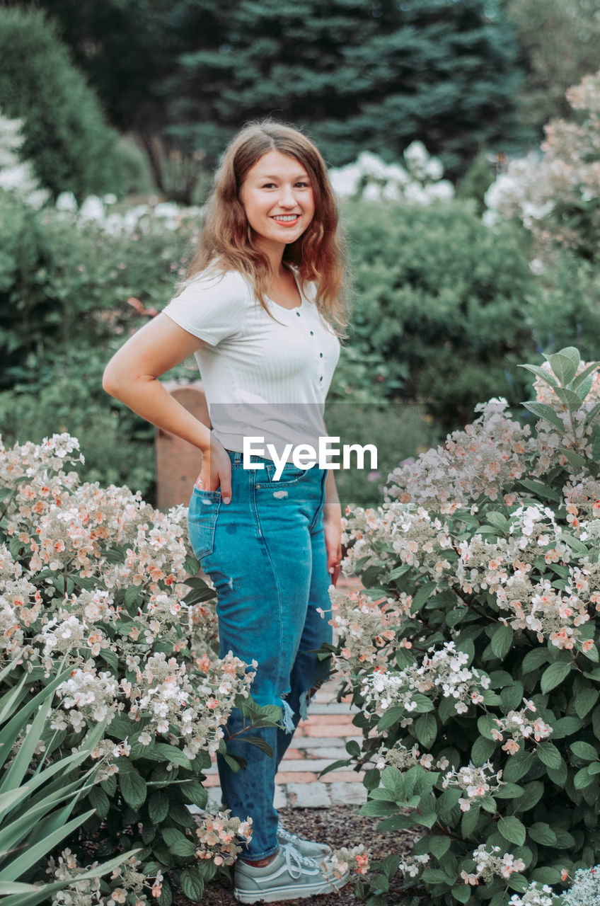 Portrait of smiling teenager standing amidst plants at park
