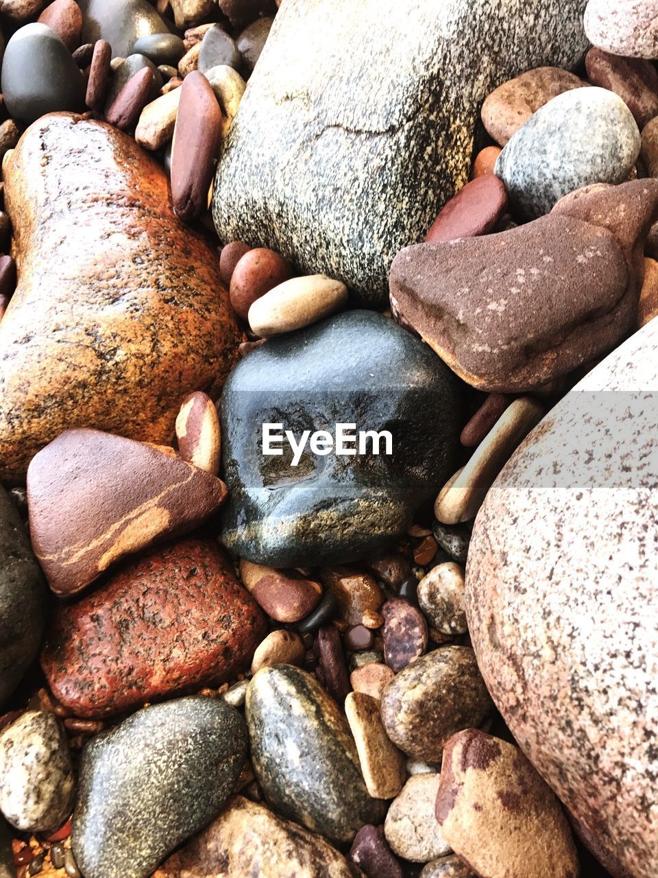 FULL FRAME SHOT OF PEBBLES ON SAND