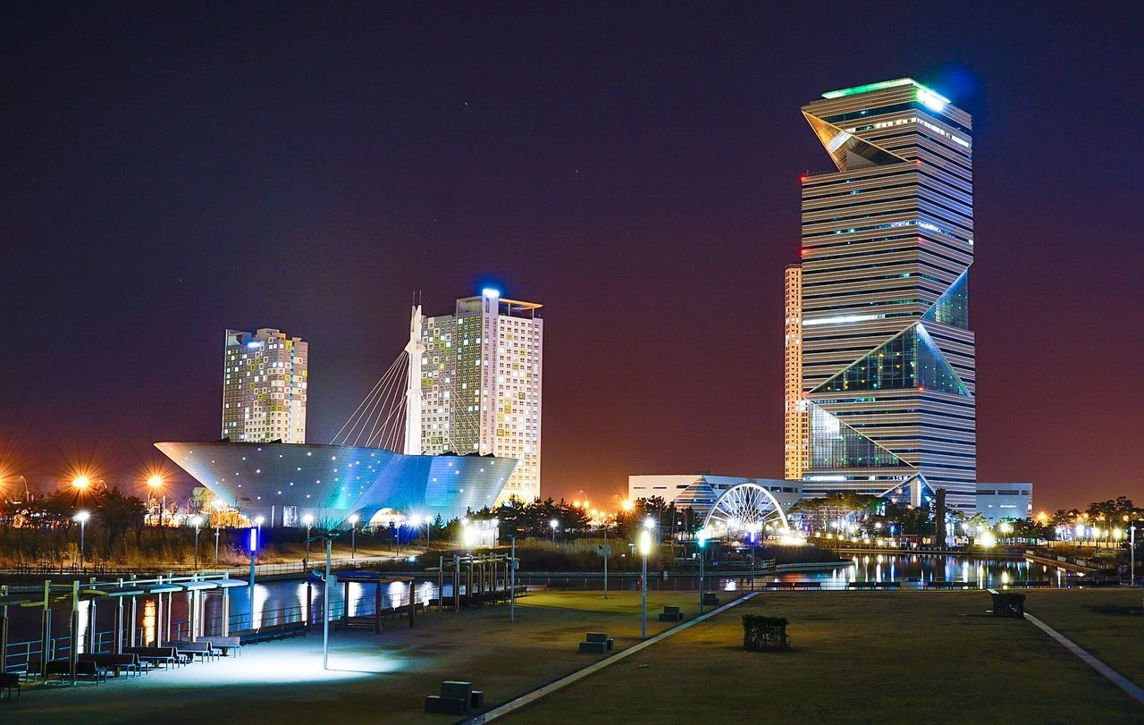 Low angle view of illuminated modern buildings against sky at night