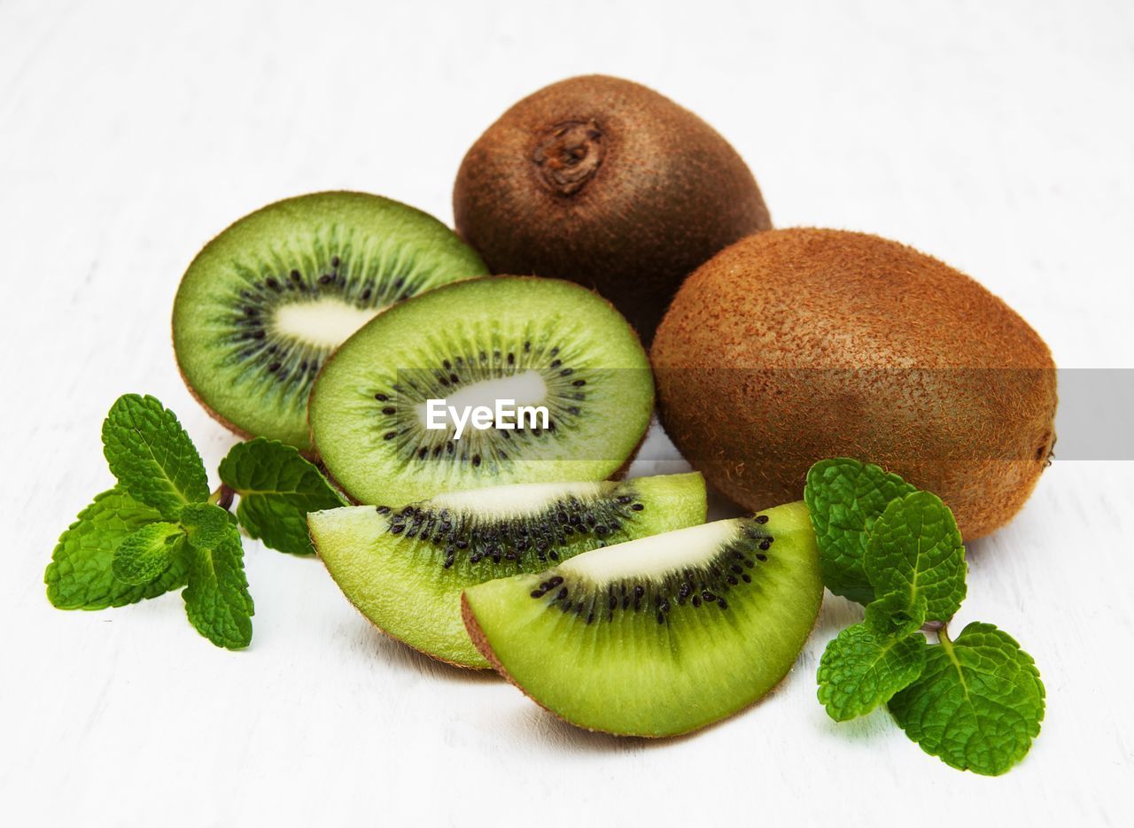 Close-up of kiwis with mint leaves against white background