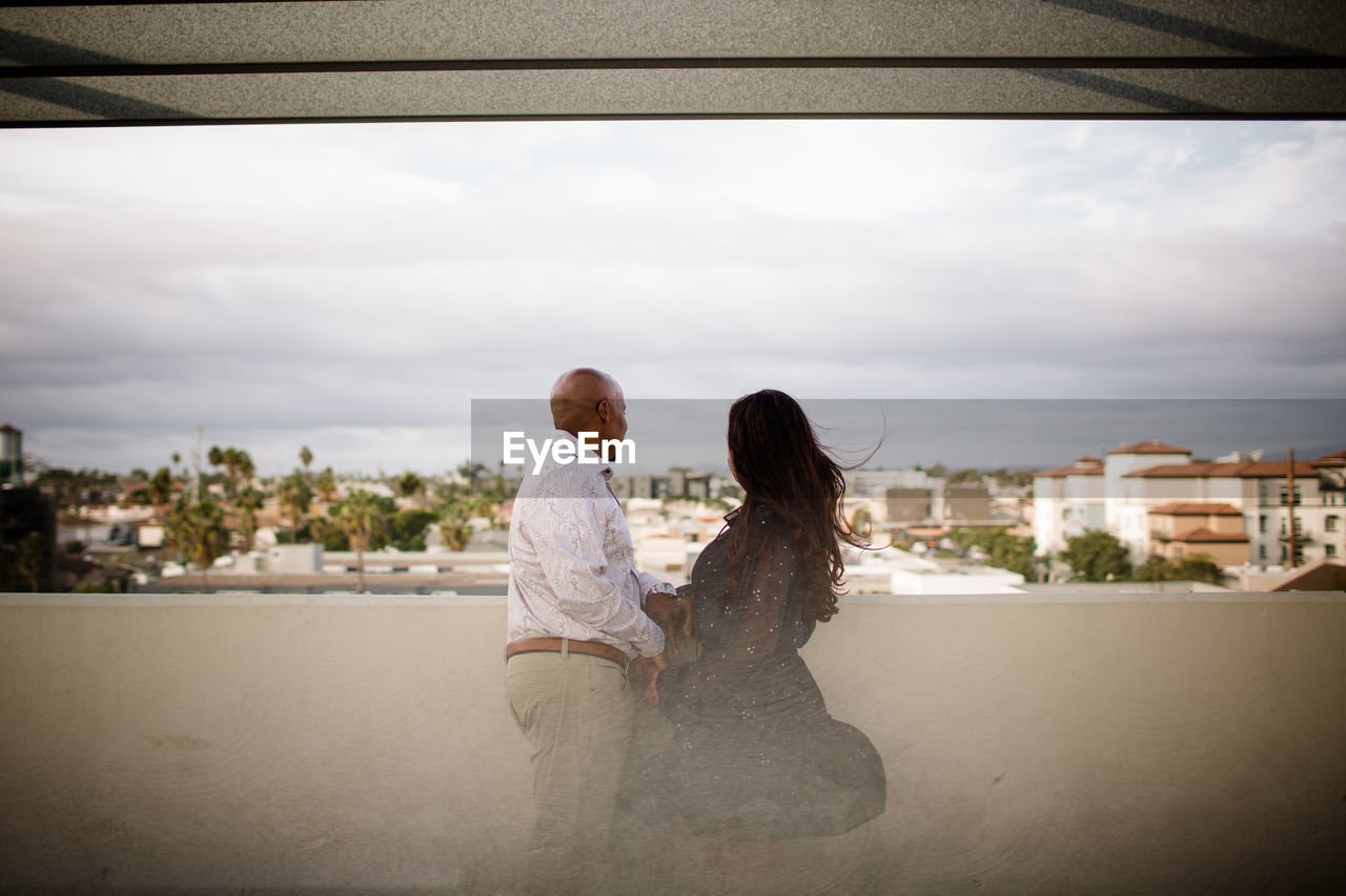 Multiracial late forties couple embracing at sunset in san diego