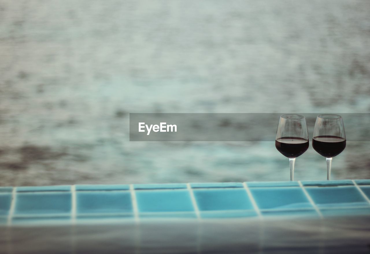 Close-up of wineglasses by swimming pool