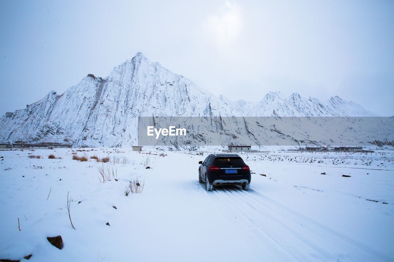 CAR ON SNOWCAPPED MOUNTAINS AGAINST SKY