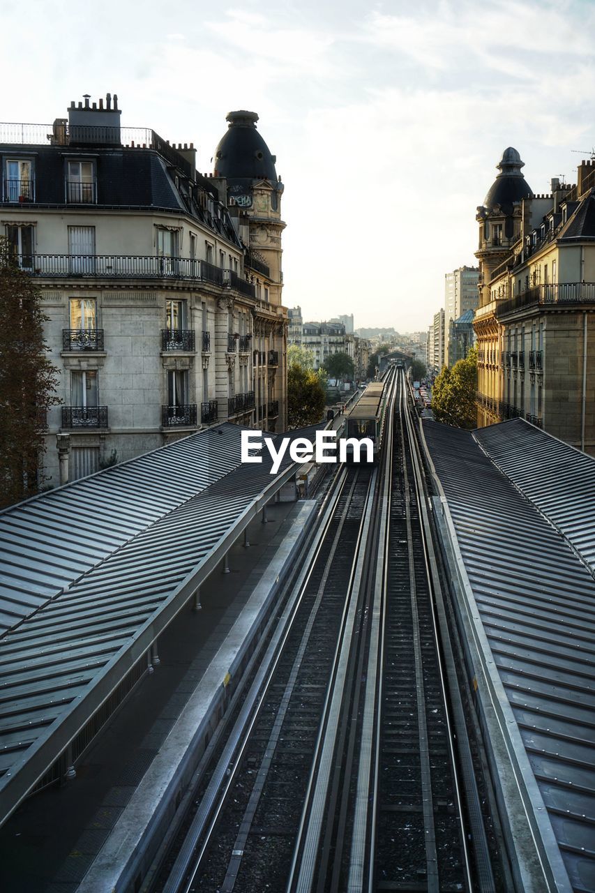 Railroad tracks amidst buildings in city against sky