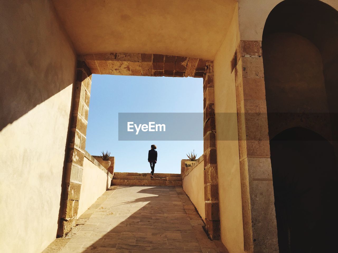 Rear view of woman walking on staircase against sky