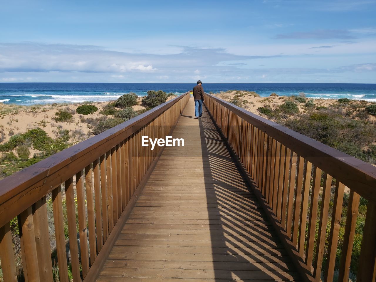 VIEW OF WOODEN FOOTBRIDGE LEADING TOWARDS SEA