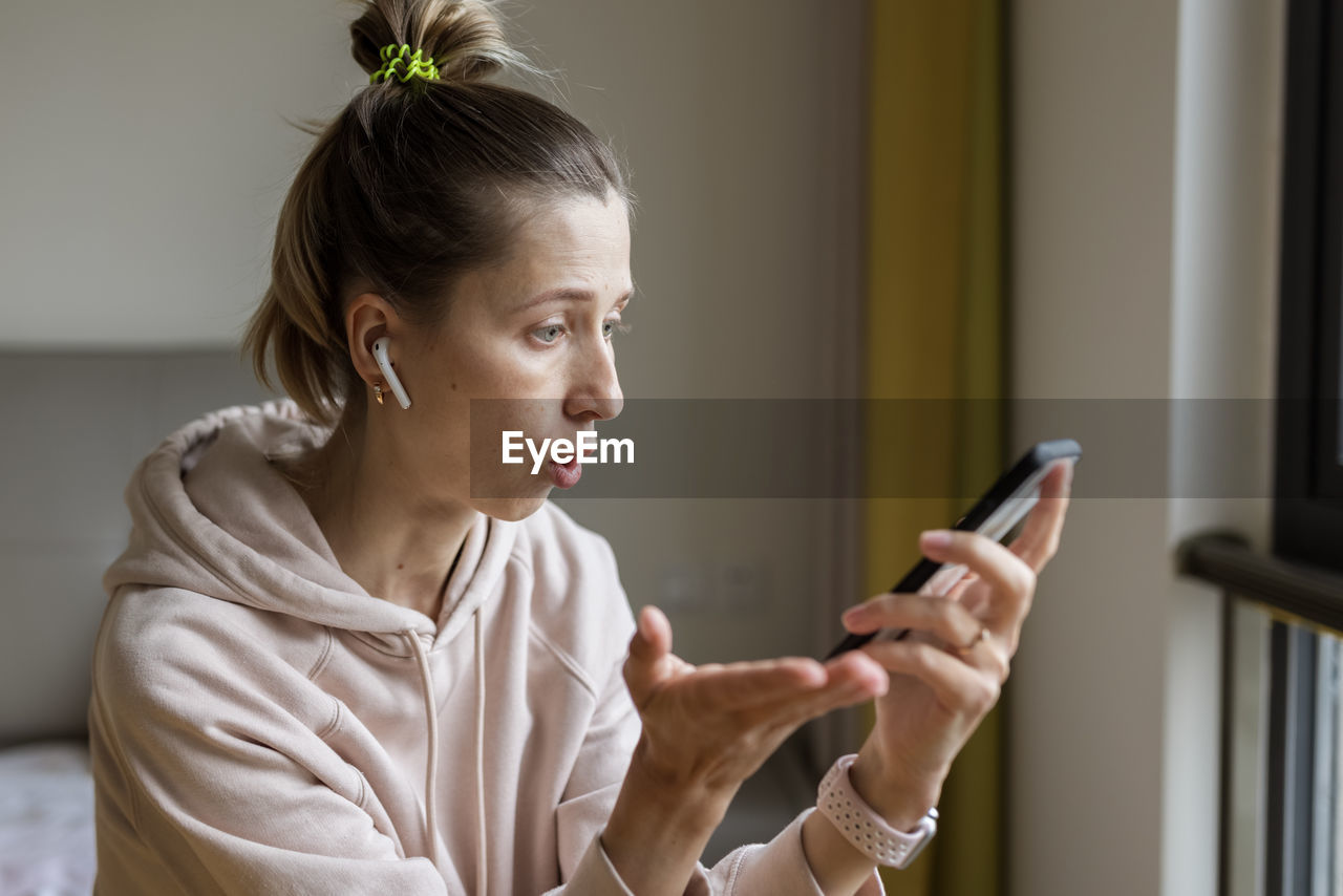 side view of young woman using mobile phone at home