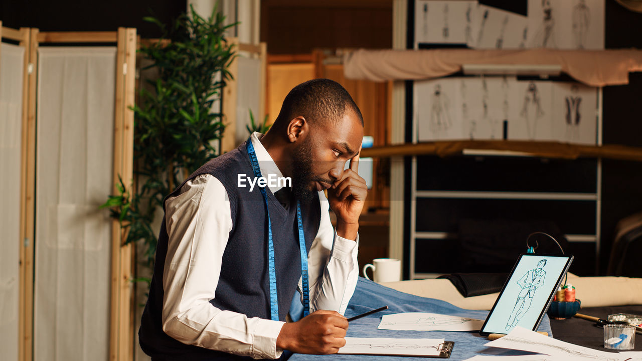 side view of man using laptop while sitting in office