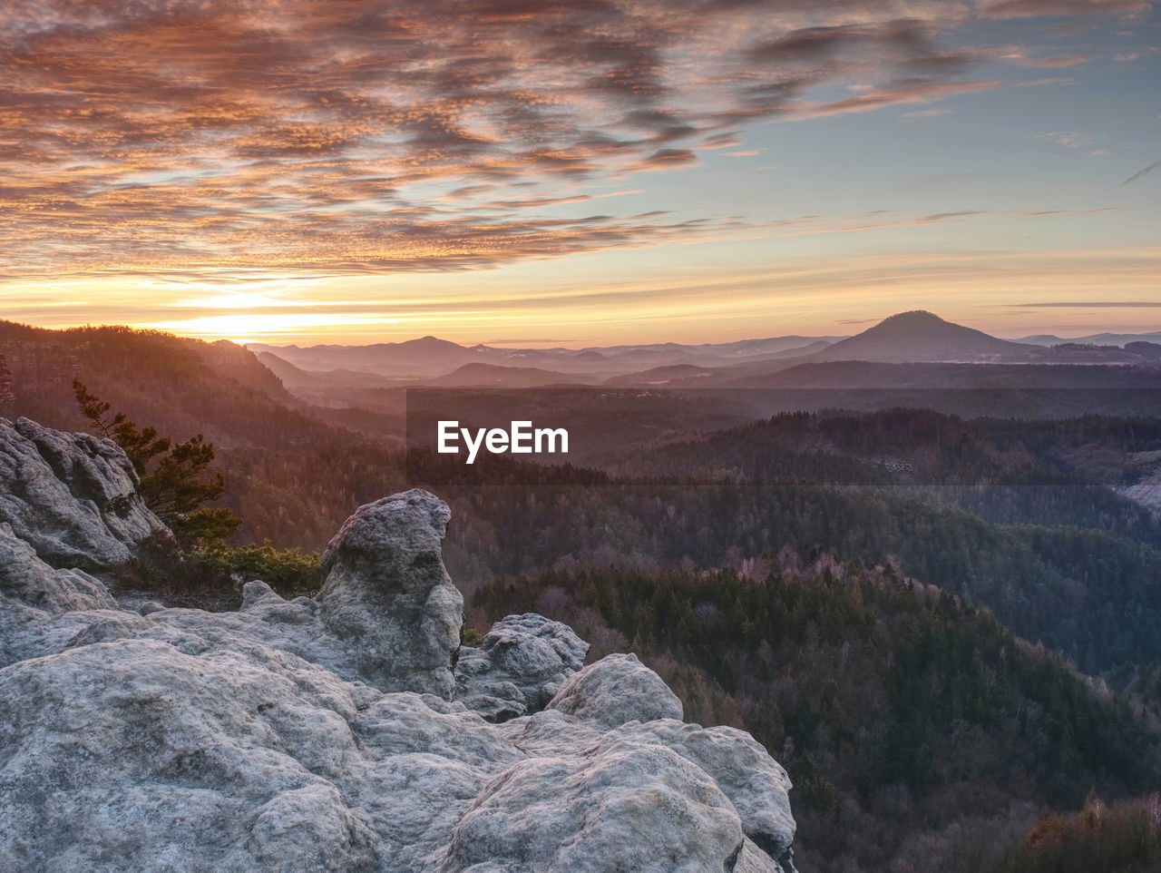 Dreamy beautiful mountain valley with a small hill peaks in the sunset rays