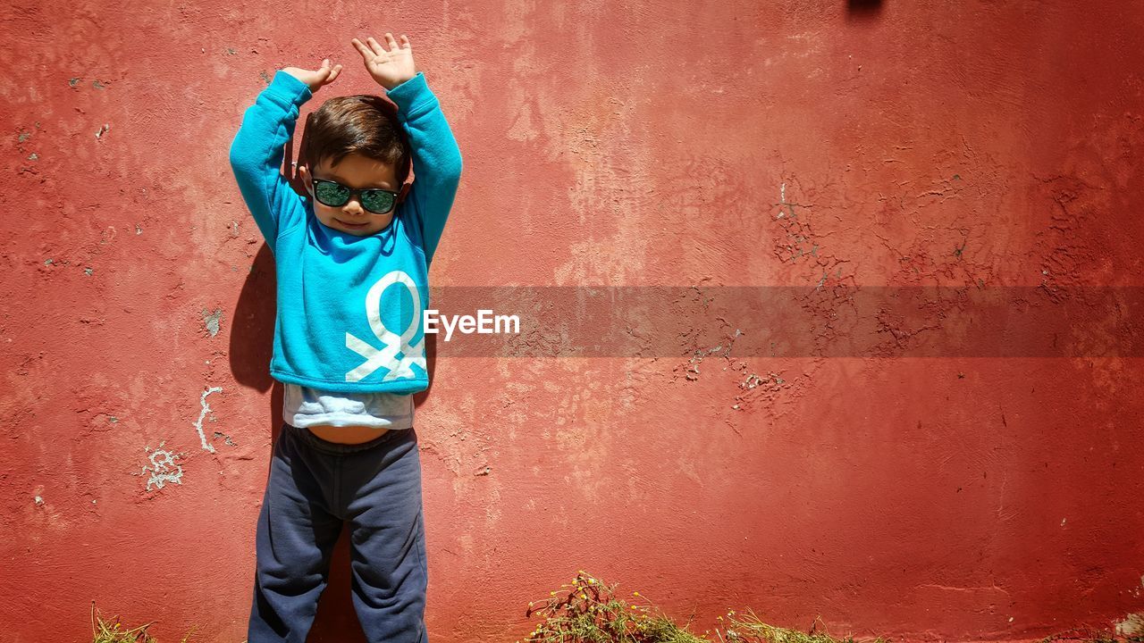 Happy young boy against red wall