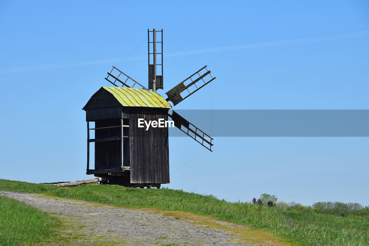 Traditional windmill on field against clear blue sky