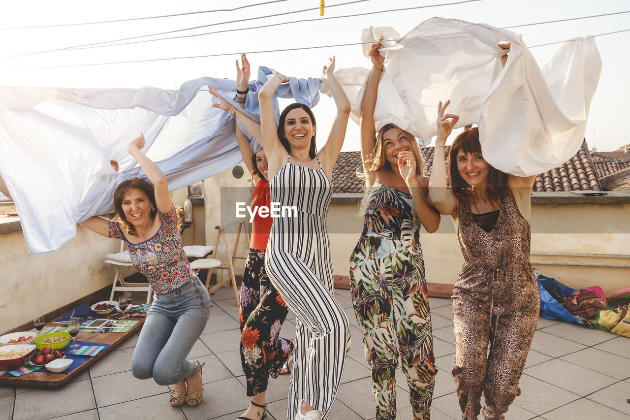 Smiling female friends enjoying on building terrace