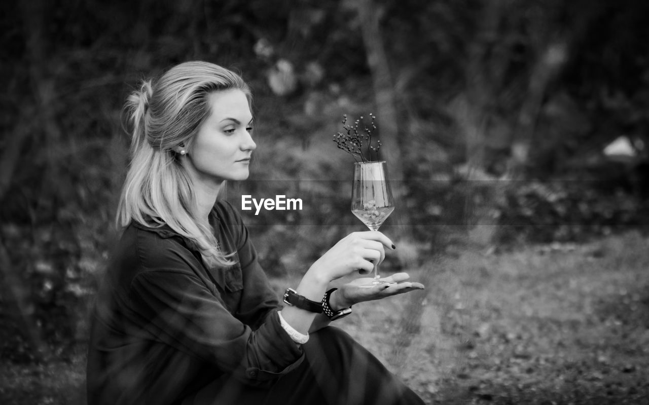 SIDE VIEW OF A YOUNG WOMAN HOLDING GLASS