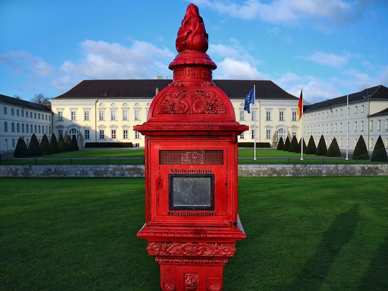 Close-up of a red monument on lawn against building exterior