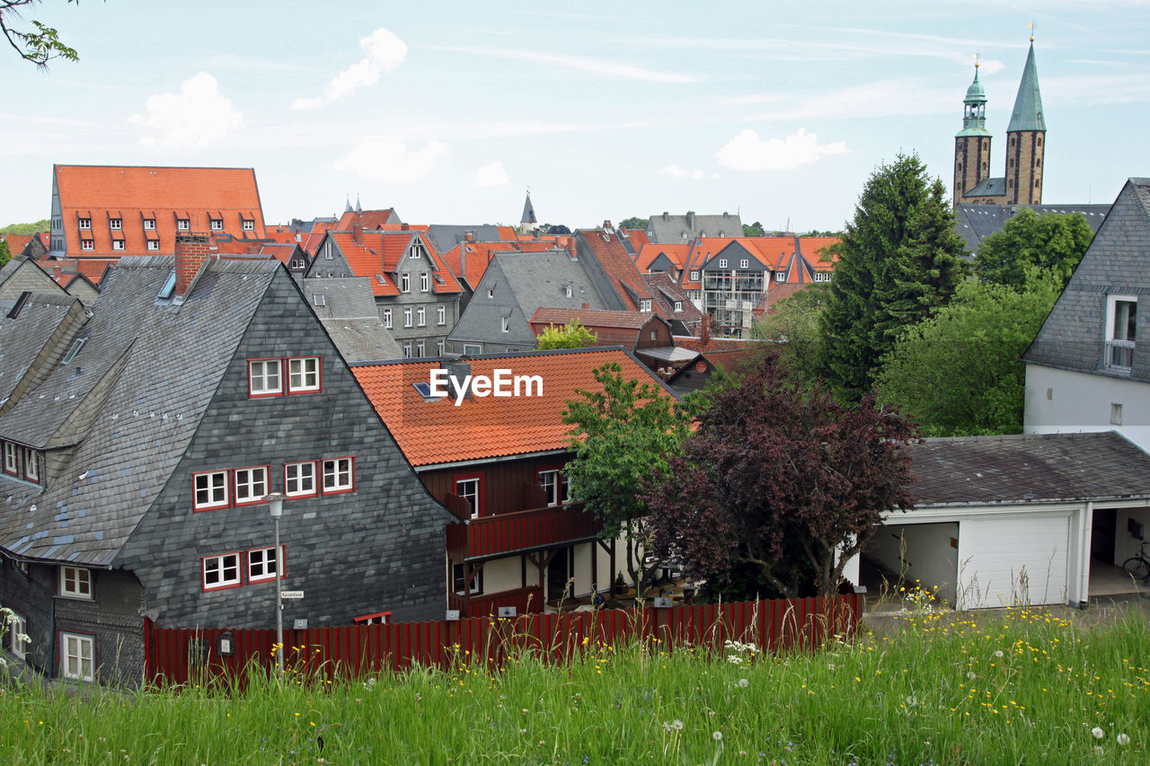 Houses by buildings in town against sky