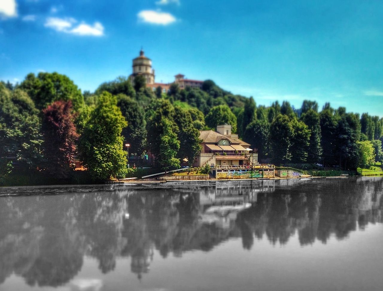 House amidst river and trees against sky