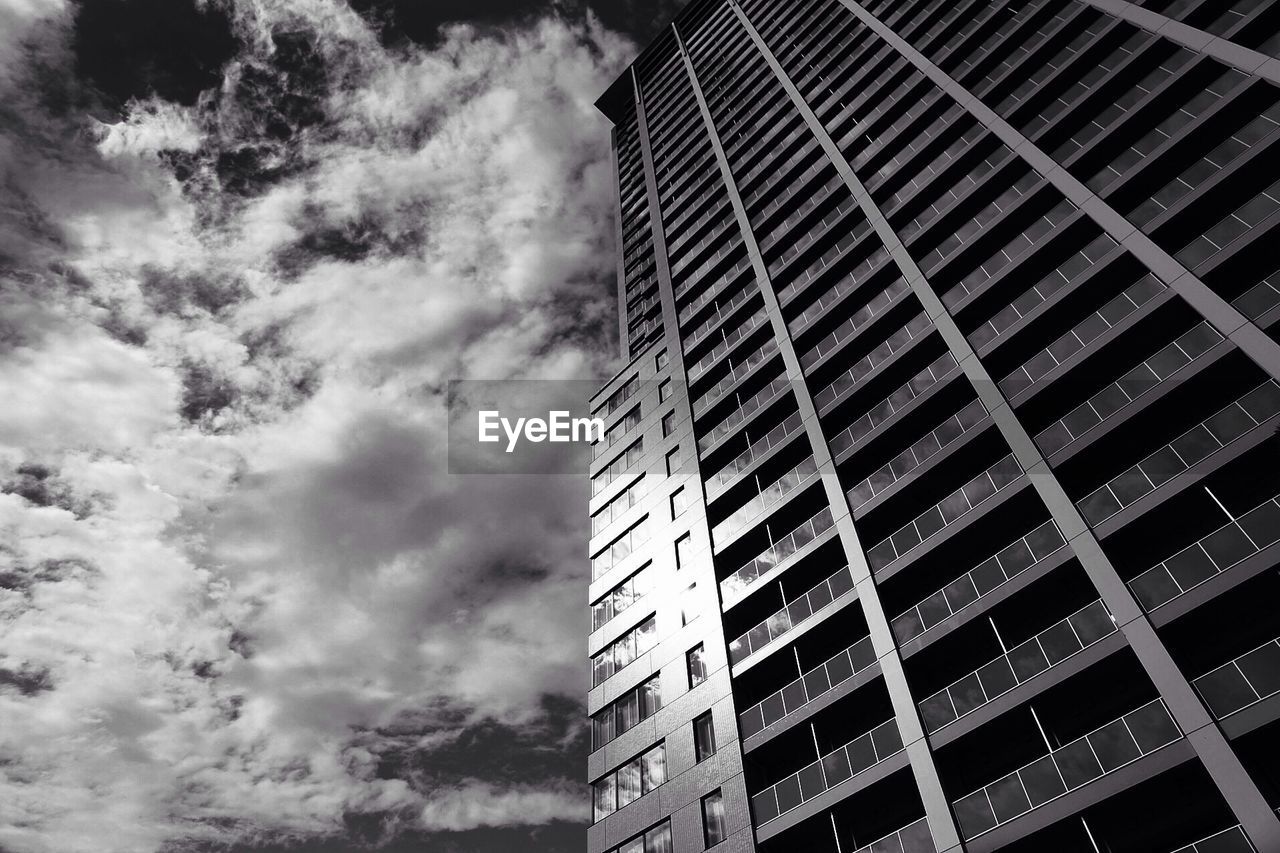 Low angle view of skyscrapers against cloudy sky