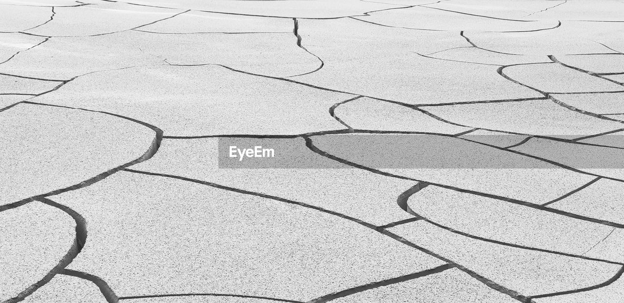 HIGH ANGLE VIEW OF CRACKED LAND ON COBBLESTONE STREET