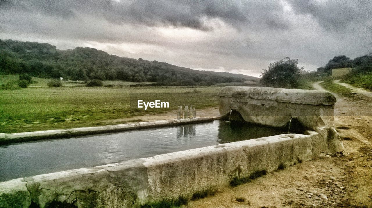 VIEW OF BUILT STRUCTURE BY WATER AGAINST SKY