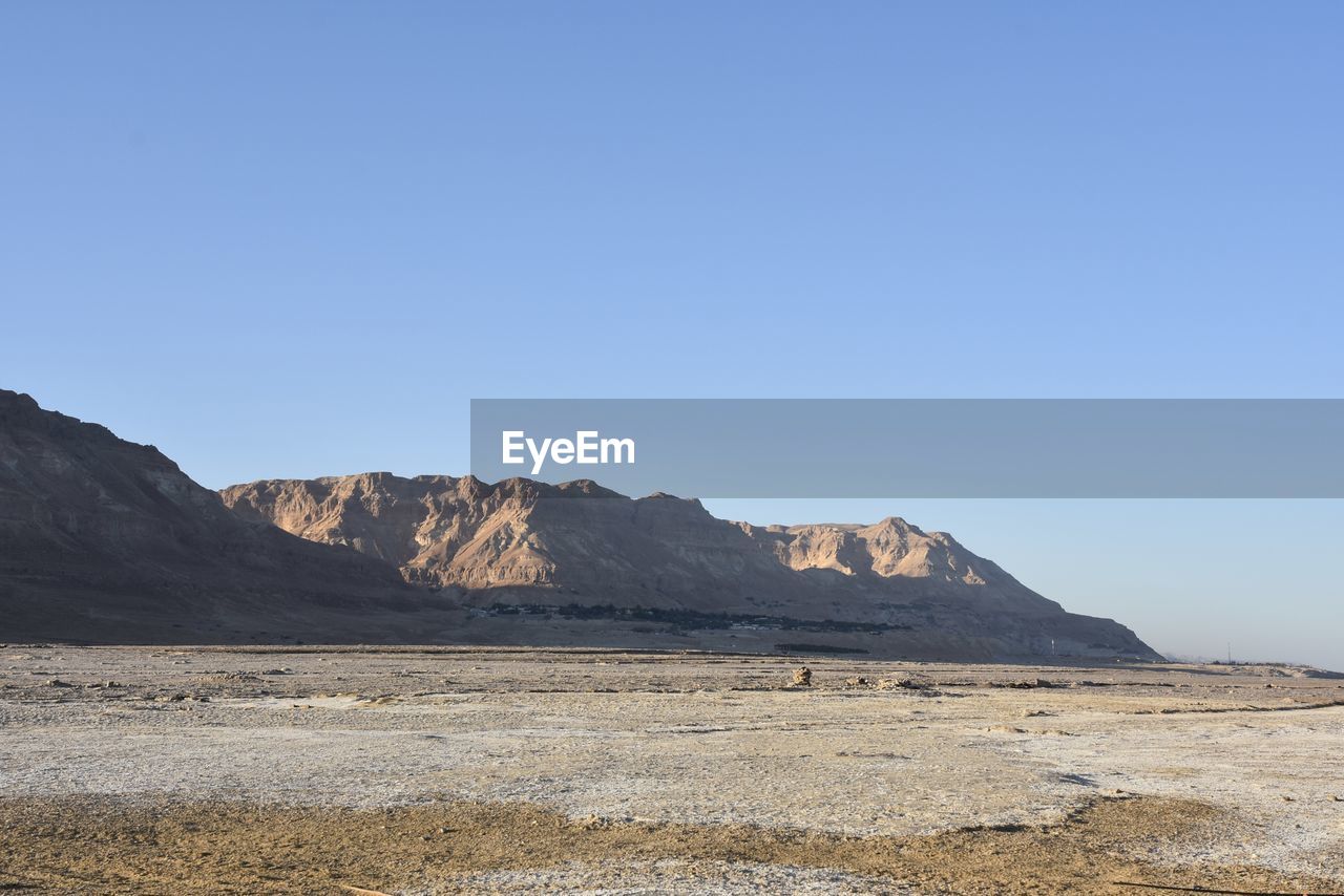 Scenic view of desert against clear blue sky