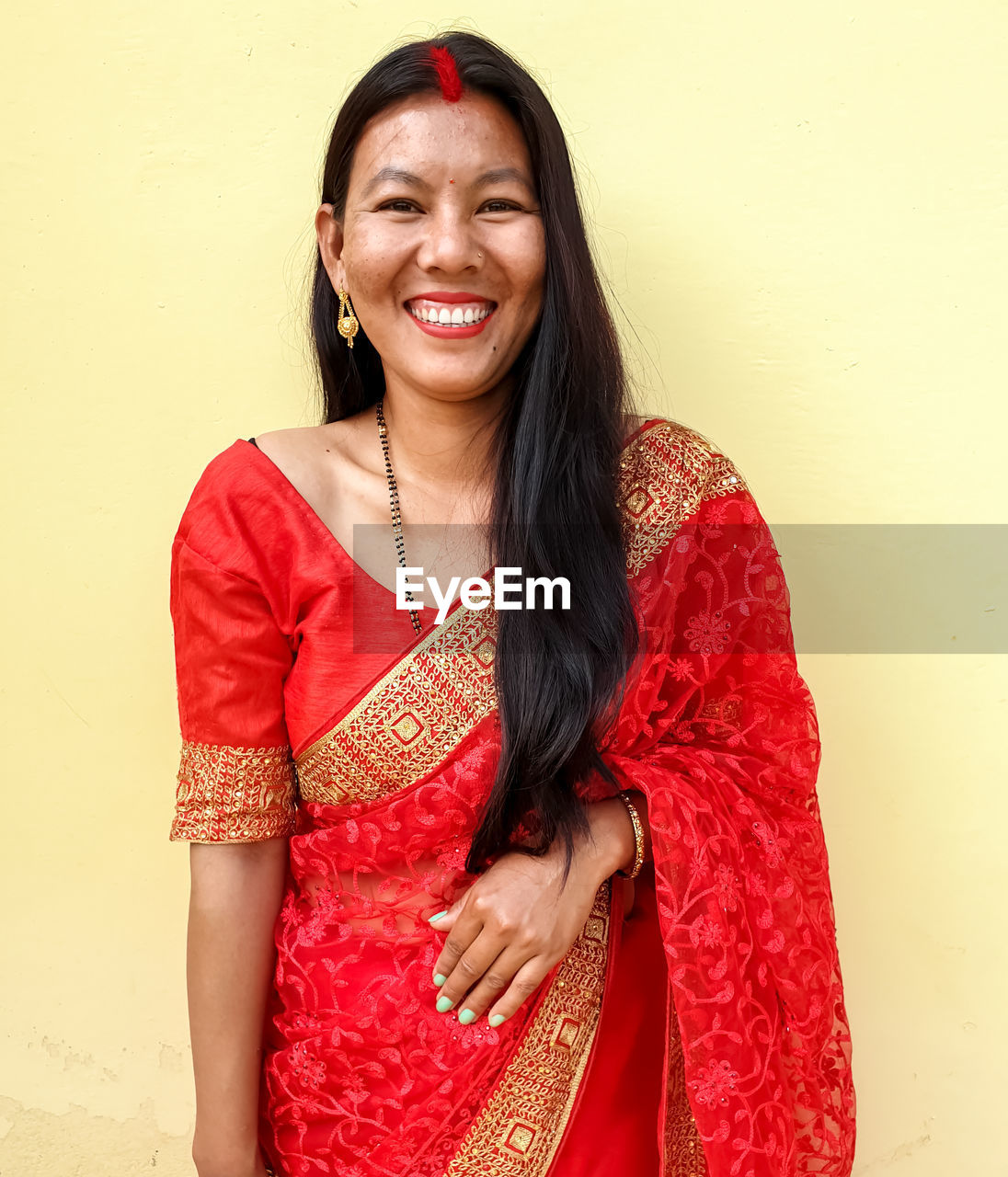 Portrait of a smiling young woman standing against wall