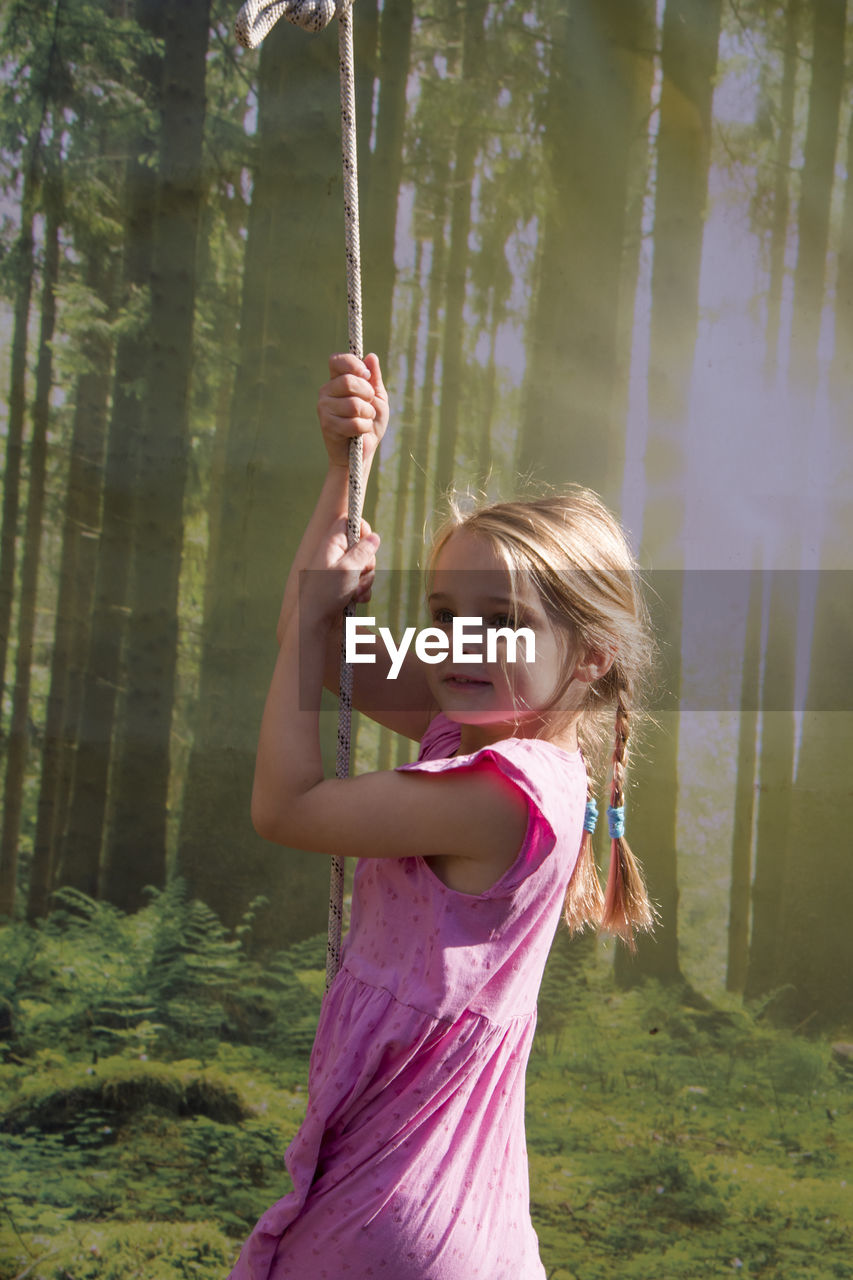 Side view of girl standing against trees in forest