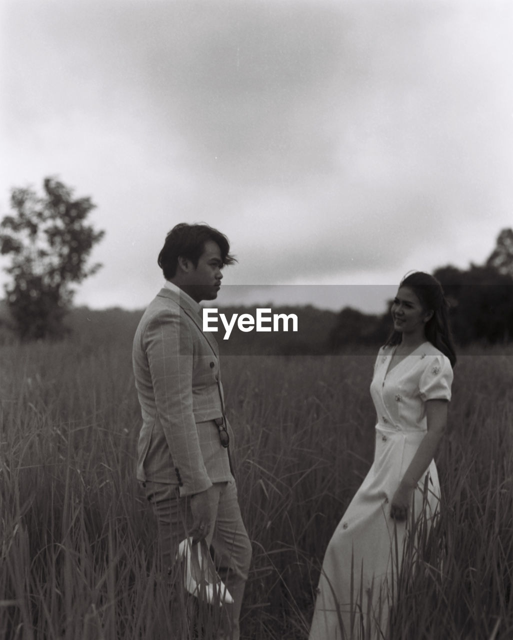 Young couple on field against sky