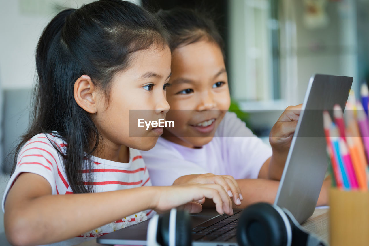 Two asian child girl students study online with teacher by video call together. 